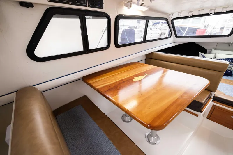 Slide: The Image of Interior of 2023 Skipjack 26 Flybridge with wooden table and cushioned seating. - 30