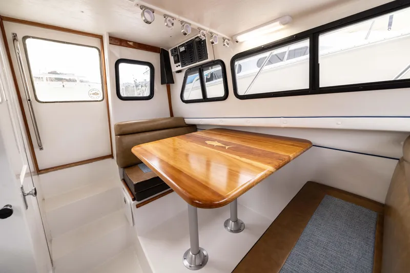 Slide: The Image of Interior of 2023 Skipjack 26 Flybridge with wooden table and cushioned seating. - 31