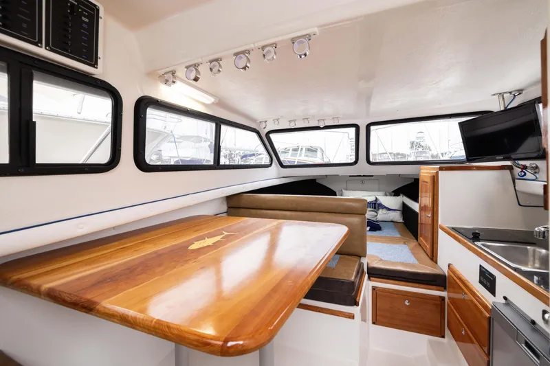 Slide: The Image of Interior of 2023 Skipjack 26 Flybridge boat with wood table and seating area. - 33