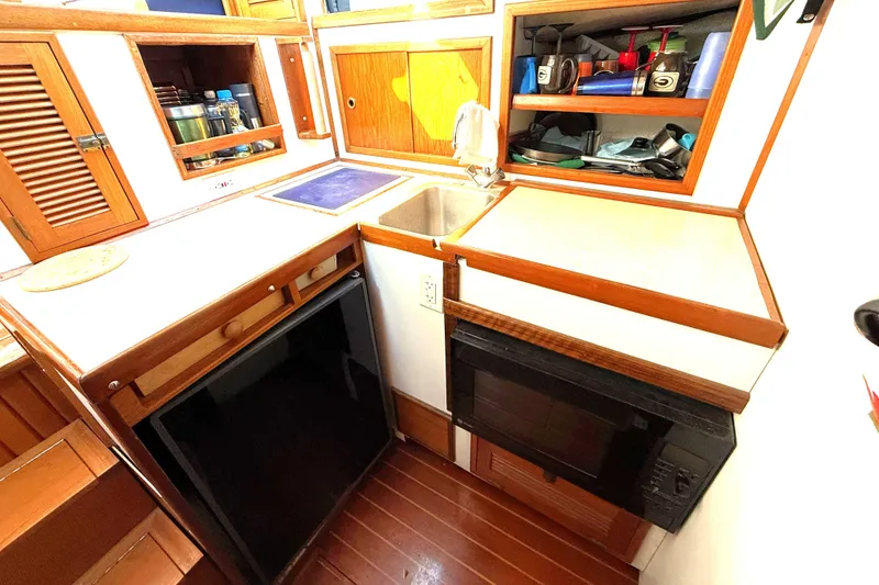 Slide: The Image of 1983 Wilbur 34 Fly Bridge Cruiser kitchen with wooden cabinets and compact appliances. - 1