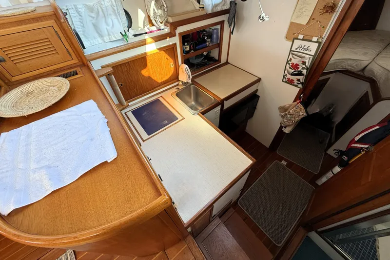 Slide: The Image of 1983 Wilbur 34 Fly Bridge Cruiser interior with compact kitchen and cozy cabin space. - 17