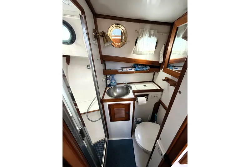 Slide: The Image of Compact bathroom in 1983 Wilbur 34 Fly Bridge Cruiser with sink, toilet, and shower. - 20