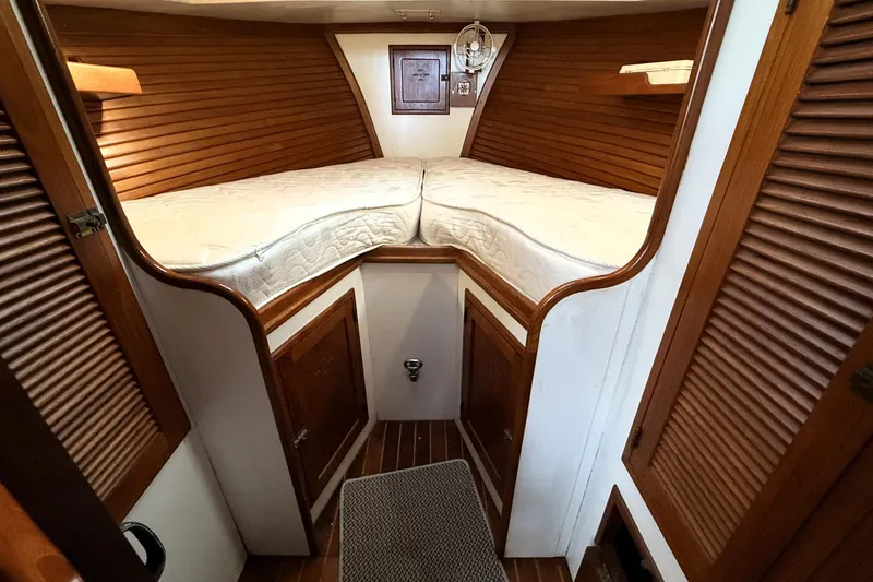 Slide: The Image of Cozy cabin interior of 1983 Wilbur 34 Fly Bridge Cruiser with wooden accents and bedding. - 22