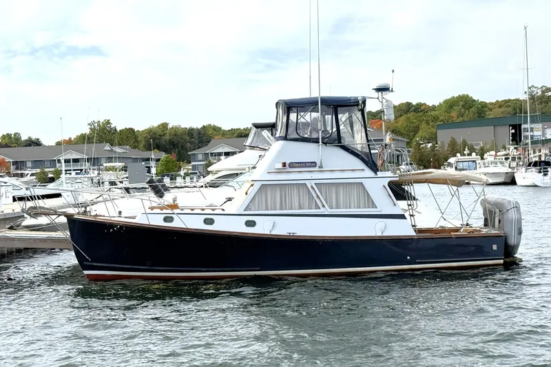 Slide: The Image of 1983 Wilbur 34 Fly Bridge Cruiser docked at marina, surrounded by other boats. - 25