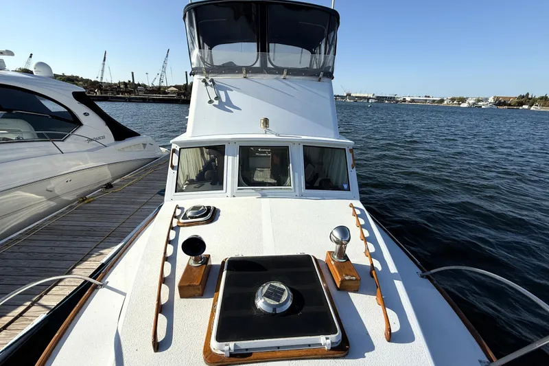 Slide: The Image of 1983 Wilbur 34 Fly Bridge Cruiser docked, showcasing deck and flybridge on a sunny day. - 36