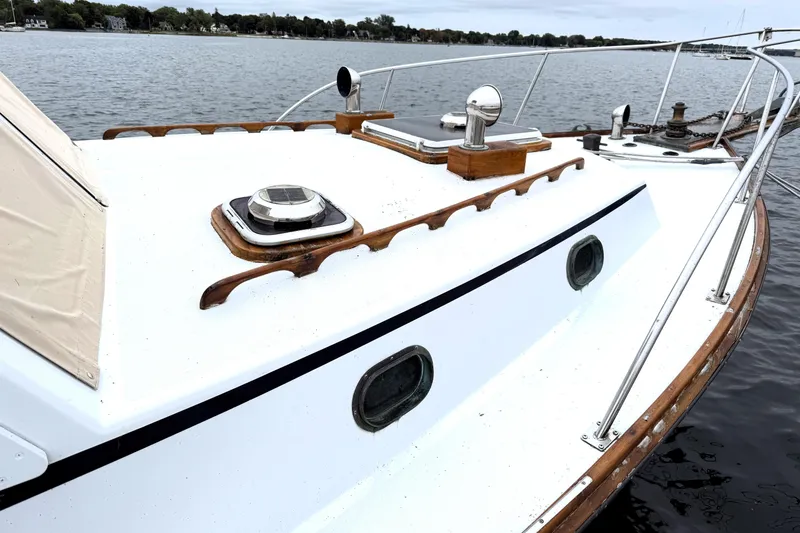 Slide: The Image of 1983 Wilbur 34 Fly Bridge Cruiser on calm water, showcasing deck and portholes. - 7