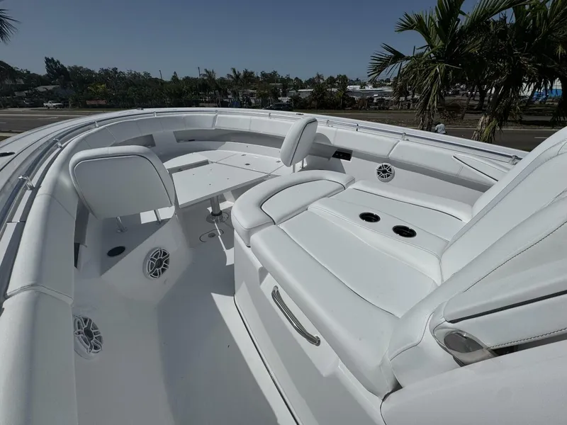 Slide: The Image of 2025 Sportsman 352 Open boat interior with white seating and table, surrounded by palm trees. - 23