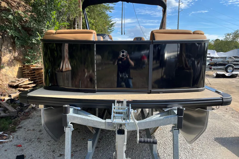 Slide: The Image of 2025 Harris Sunliner 250 pontoon boat on trailer, featuring sleek black exterior and tan seating. - 1