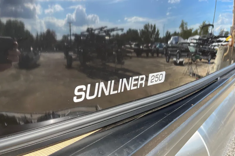 Slide: The Image of 2025 Harris Sunliner 250 boat with reflective surface and outdoor background. - 3