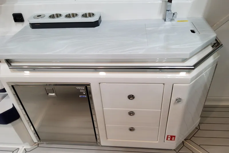 Slide: The Image of 2026 Formula 380 Super Sport Crossover OB boat kitchenette with sink, storage, and stainless steel fridge. - 46