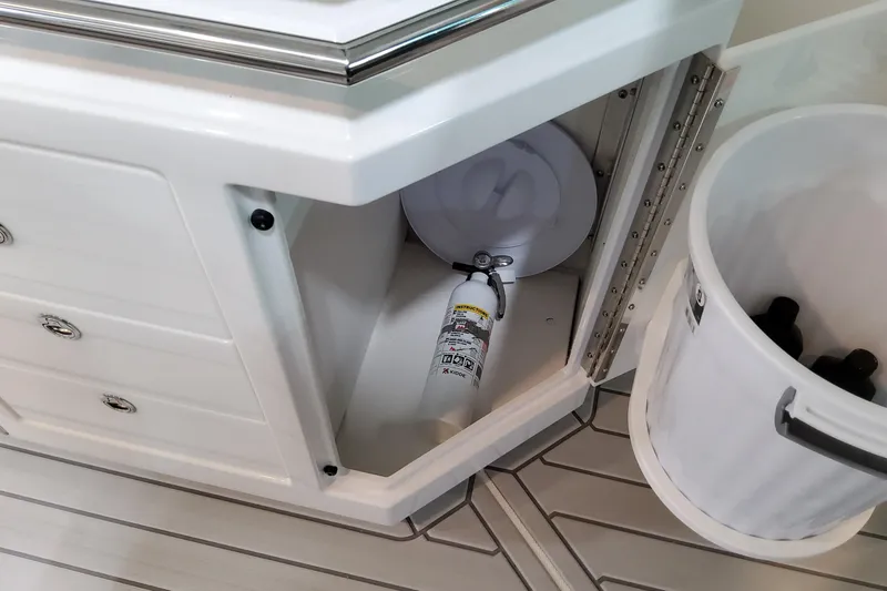 Slide: The Image of Open storage compartment on 2026 Formula 380 Super Sport Crossover OB boat with fire extinguisher. - 49