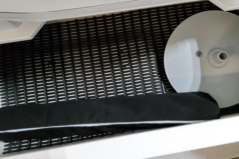 Slide: The Image of Storage compartment in 2026 Formula 380 Super Sport Crossover OB boat, featuring black mesh and circular component. - 64