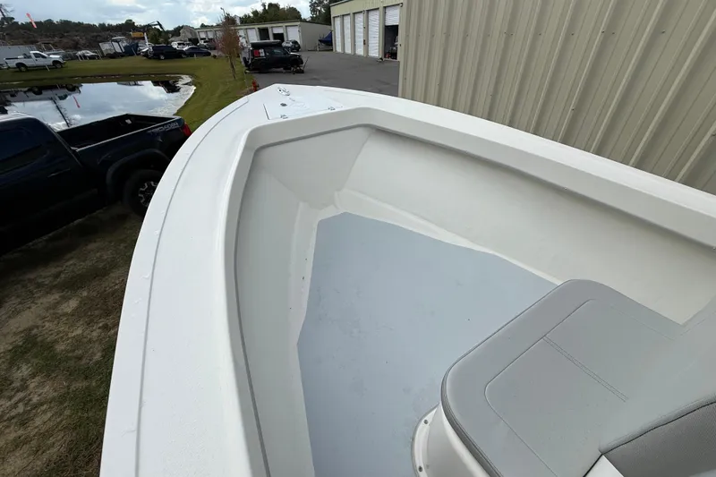 Slide: The Image of 2024 May-Craft 20 Cape Classic boat interior with seating, parked near a pond and buildings. - 9