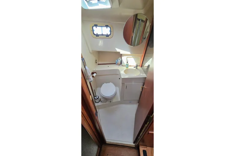 Slide: The Image of 2000 Mainship 390 Trawler bathroom with toilet, sink, and mirror. - 11