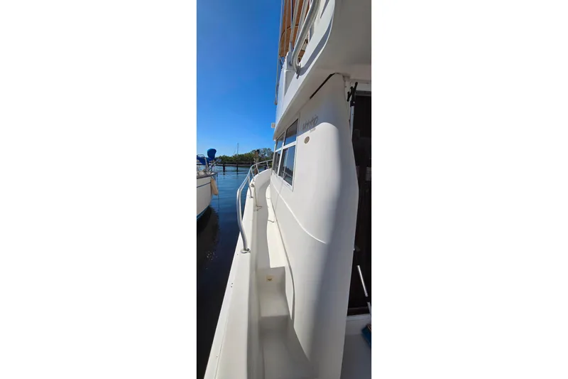 Slide: The Image of Side view of a 2000 Mainship 390 Trawler docked on a sunny day. - 13