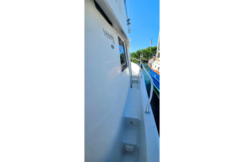 Slide: The Image of 2000 Mainship 390 Trawler side view with railing, docked near other boats. - 15