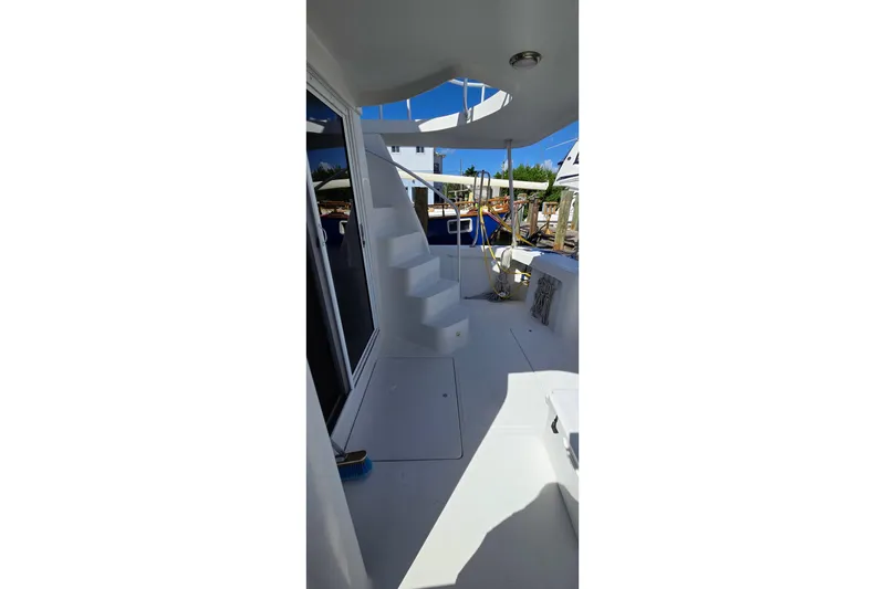 Slide: The Image of 2000 Mainship 390 Trawler deck with stairs, docked under clear blue sky. - 18