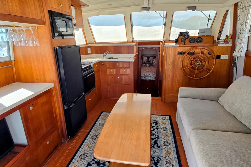 Slide: The Image of Interior of 2000 Mainship 390 Trawler with wood finish, kitchenette, and helm station. - 2