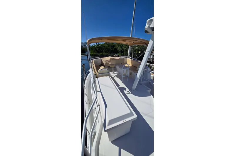 Slide: The Image of 2000 Mainship 390 Trawler deck with seating and canopy under clear blue sky. - 22