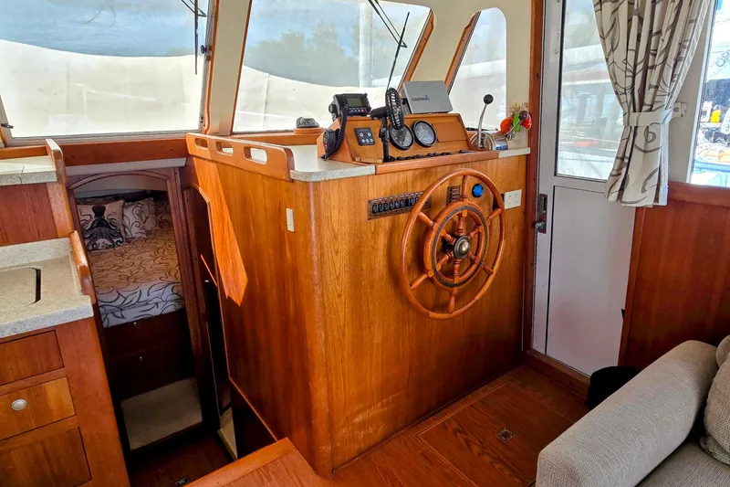 Slide: The Image of 2000 Mainship 390 Trawler interior with wooden helm, navigation equipment, and cozy cabin. - 3