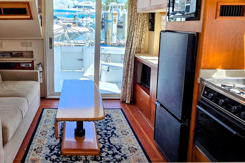Slide: The Image of Interior of 2000 Mainship 390 Trawler with cozy seating, kitchen, and marina view. - 5