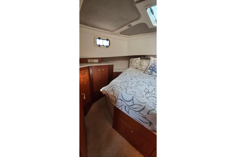 Slide: The Image of Cozy cabin interior of 2000 Mainship 390 Trawler with elegant bedding and wooden cabinetry. - 9