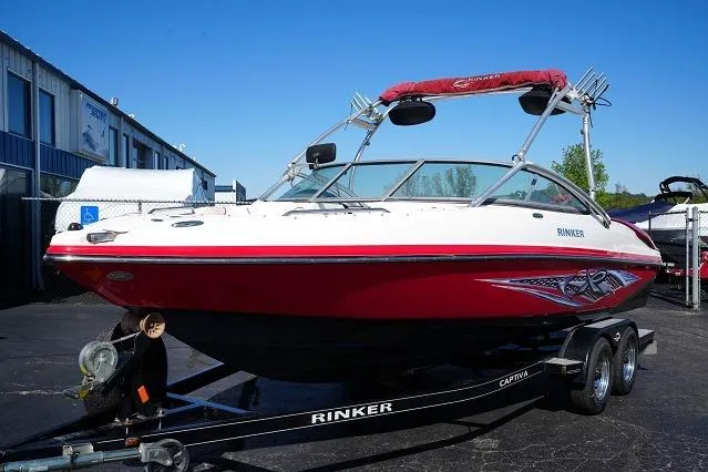 Slide: The Image of 2007 Rinker 226 Captiva Bowrider boat on trailer, red and white design, parked outdoors. - 1