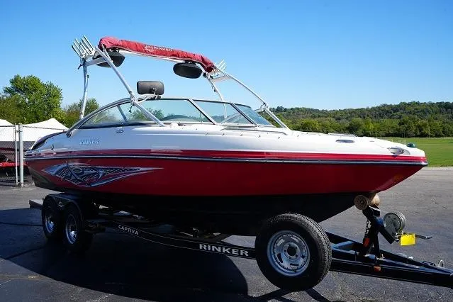 Slide: The Image of 2007 Rinker 226 Captiva Bowrider boat on trailer, red and white design, parked outdoors. - 2