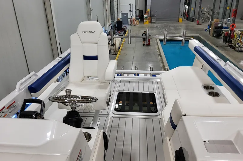 Slide: The Image of 2026 Formula 457 Center Console Fish boat interior with steering wheel and seating in a workshop. - 24