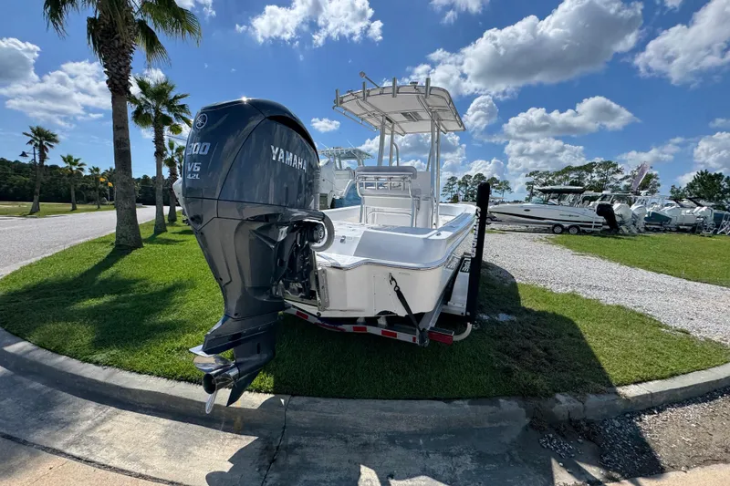 Slide: The Image of 2026 Contender 26 Bay boat with Yamaha engine, parked on grass under a blue sky. - 11