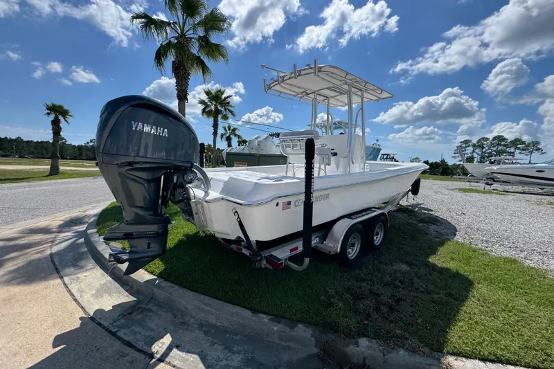 Slide: The Image of 2026 Contender 26 Bay boat with Yamaha engine on trailer, parked under palm trees. - 12