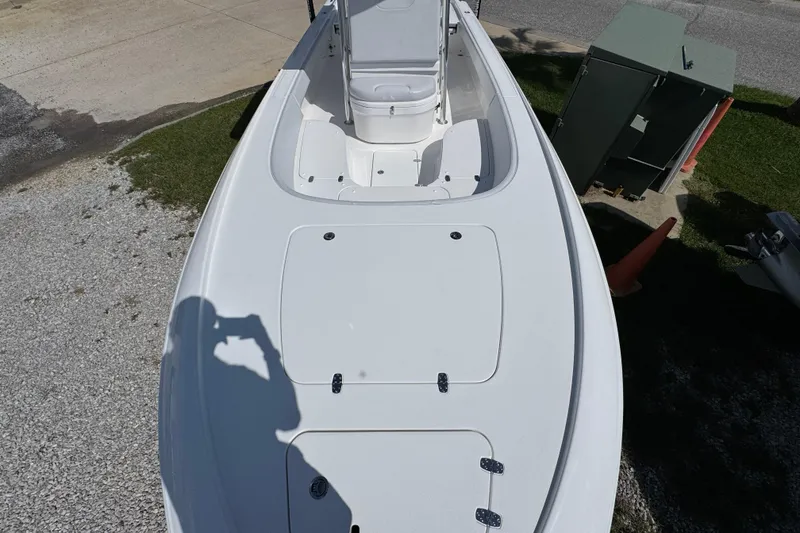 Slide: The Image of 2026 Contender 26 Bay boat deck view, parked on gravel and grass. - 17