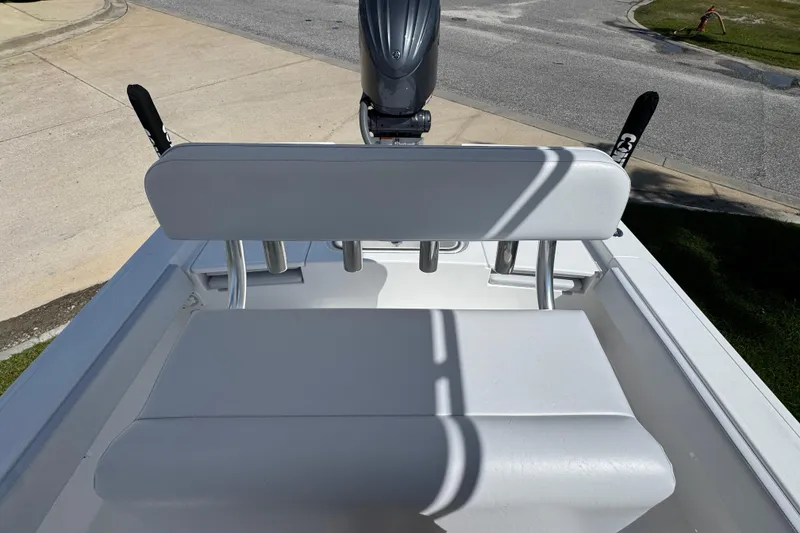 Slide: The Image of 2026 Contender 26 Bay boat with white seating and motor, parked on pavement. - 23