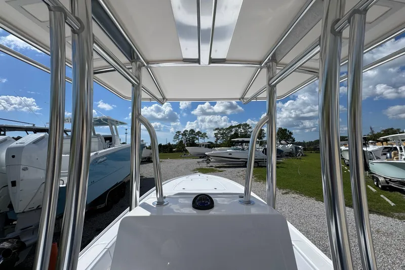 Slide: The Image of 2026 Contender 26 Bay boat interior with T-top, parked outdoors under a blue sky. - 27