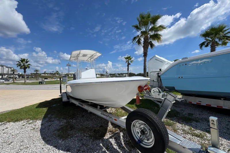 Slide: The Image of 2026 Contender 26 Bay boat on trailer under clear blue sky with palm trees. - 4