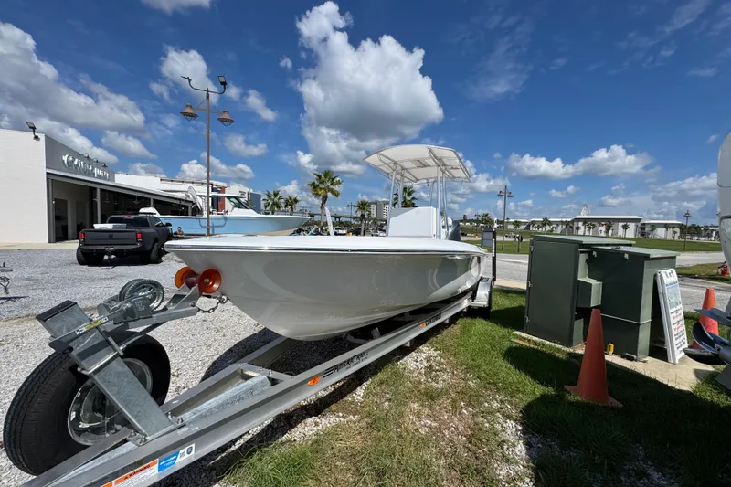Slide: The Image of 2026 Contender 26 Bay boat on trailer under blue sky at dealership. - 6