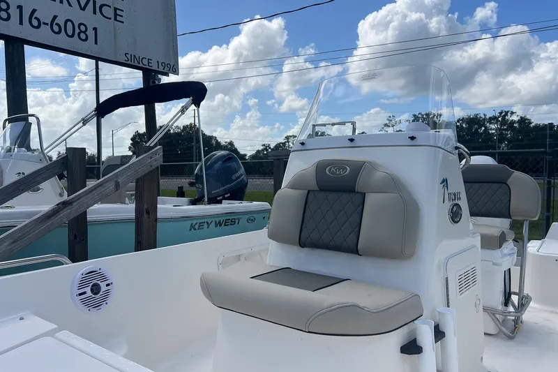Slide: The Image of 2026 Key West 1720 Center Console boat with cushioned seating, parked outdoors under a cloudy sky. - 5
