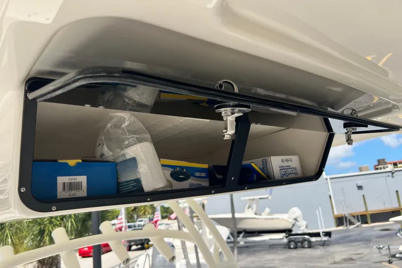 Slide: The Image of 2026 Key West 291 FS boat storage compartment with supplies, open hatch, and clear sky background. - 46