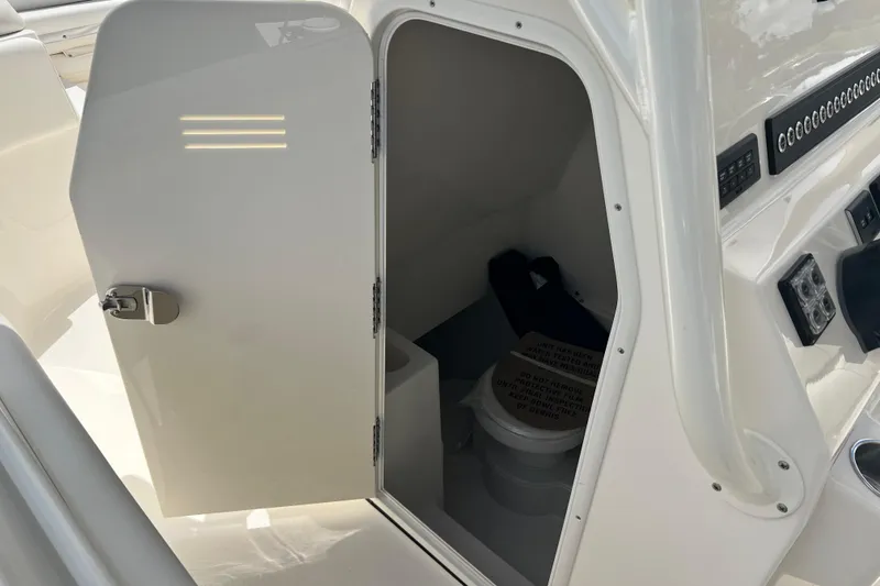 Slide: The Image of 2026 Key West 291 FS boat interior with open storage compartment and visible toilet. - 49