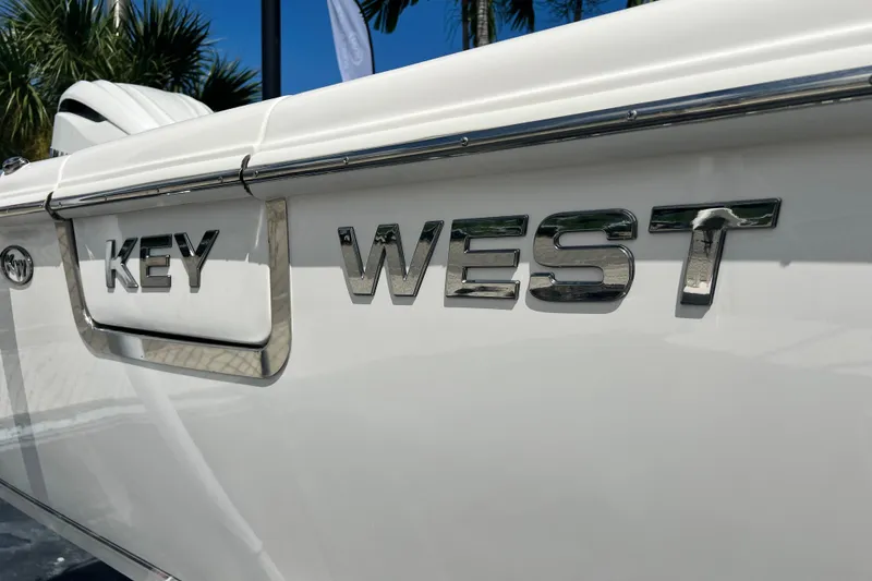 Slide: The Image of 2026 Key West 291 FS boat with chrome lettering, palm trees in background. - 60
