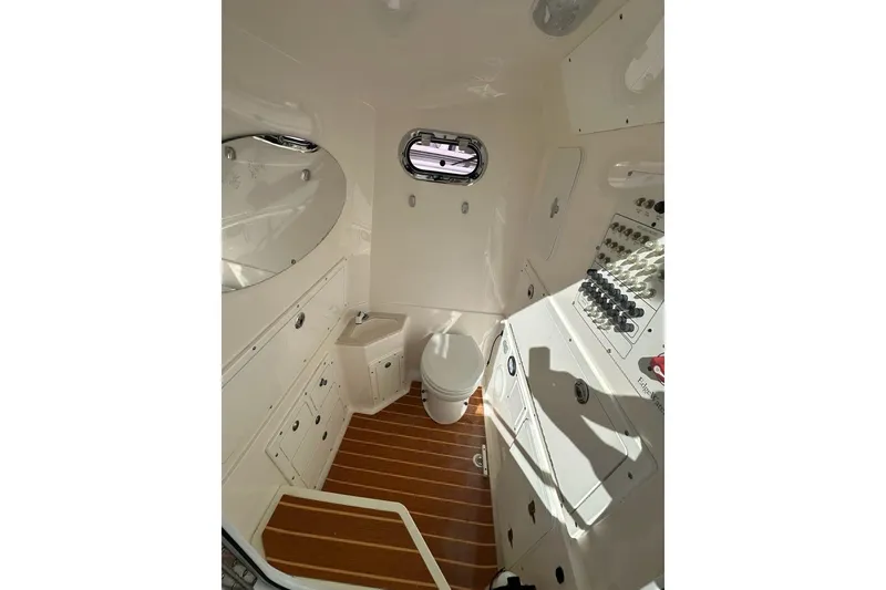 Slide: The Image of Interior of 2015 Edgewater 320CC boat featuring a compact bathroom with wooden flooring. - 14
