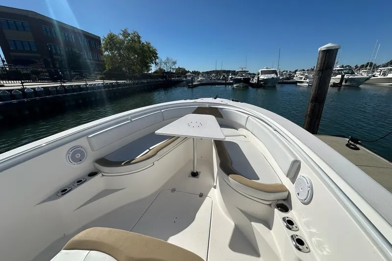 Slide: The Image of 2015 Edgewater 320CC boat docked at marina, featuring spacious seating and table. - 20