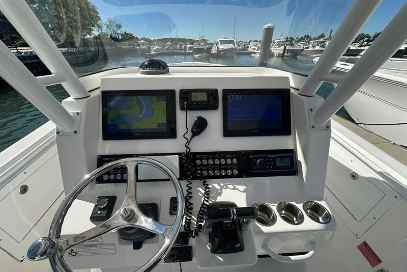 Slide: The Image of 2015 Edgewater 320CC boat dashboard with navigation screens and steering wheel in marina setting. - 9