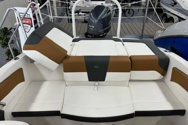 Slide: The Image of 2024 Chaparral 19 SSi OB boat interior with cushioned seating and outboard motor. - 11