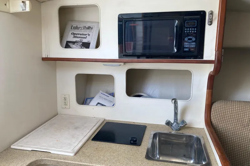 Slide: The Image of 2006 Luhrs 28 boat kitchenette with microwave, sink, and storage compartments. - 16