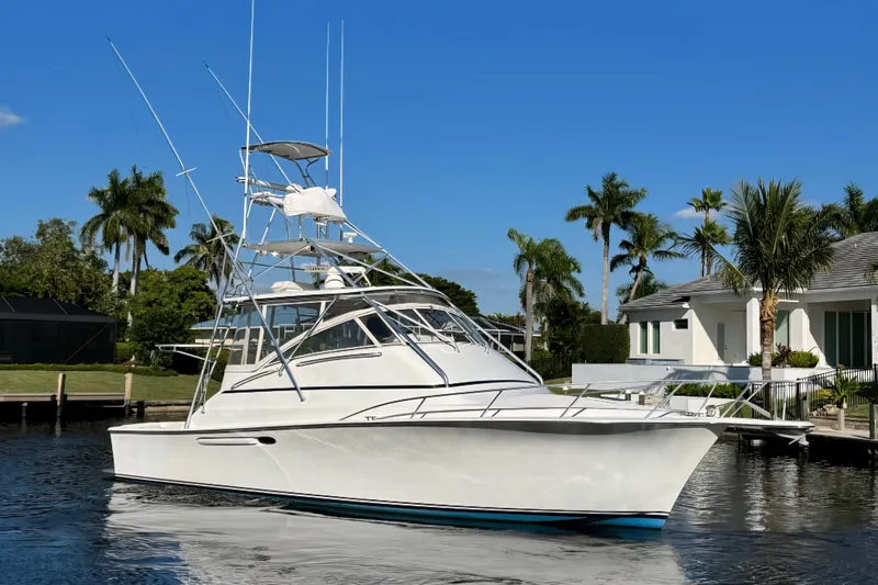 Slide: The Image of 1999 Ocean Yachts 40 Open boat docked by a waterfront home with palm trees. - 1