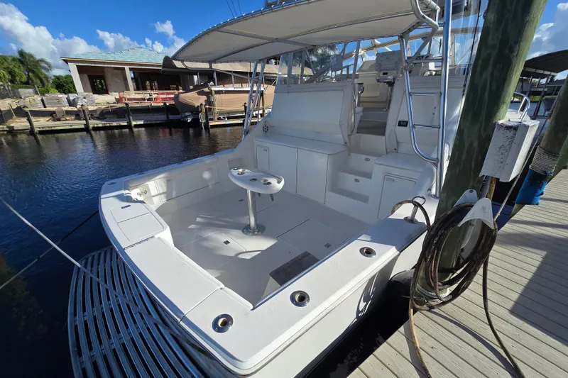 Slide: The Image of 1999 Ocean Yachts 40 Open boat docked, featuring spacious deck and seating area under clear blue sky. - 14