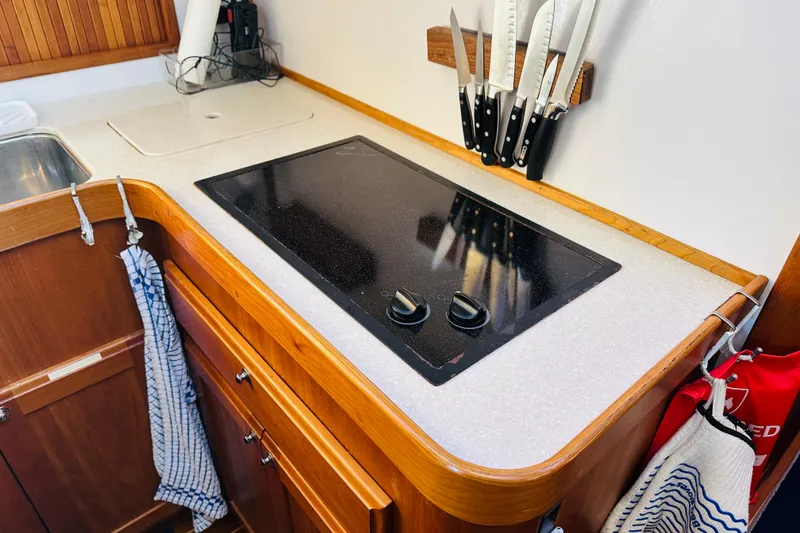 Slide: The Image of 2006 Sabre 42 Fly Bridge kitchen with stove, knives, and wooden cabinetry. - 24