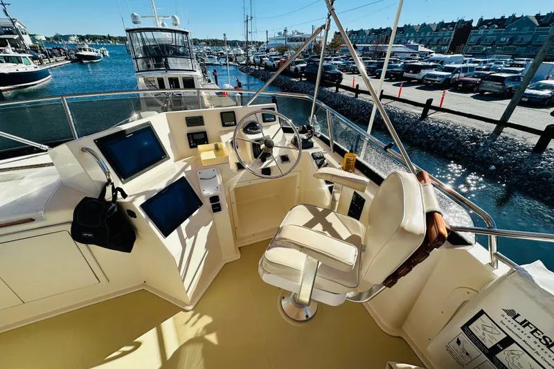 Slide: The Image of Flybridge of 2006 Sabre 42, featuring helm controls and navigation screens, docked at marina. - 51