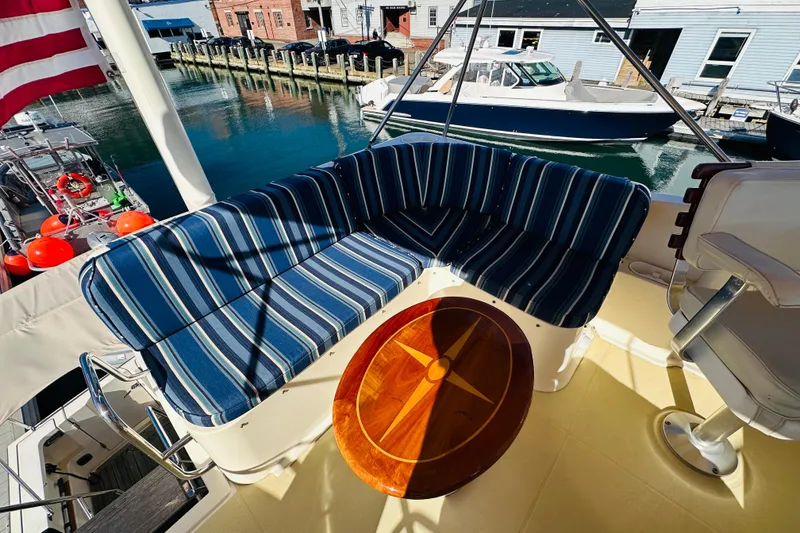 Slide: The Image of 2006 Sabre 42 Fly Bridge with striped seating and wooden table, docked at marina. - 55